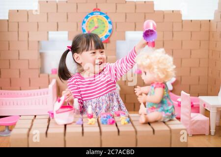 toddler girl pretend play babysitting with baby doll at home Stock Photo