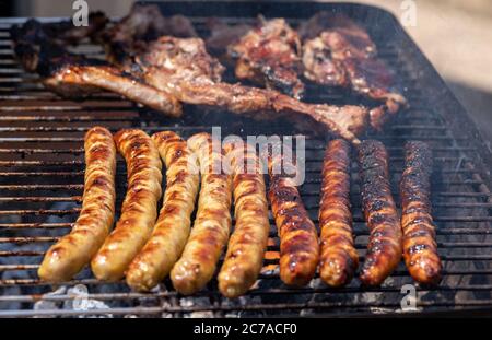 Grilled barbecue sausages and sheep meat on the grill outdoors. Stock Photo