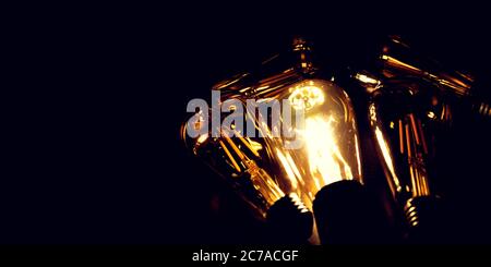 Invention, ideas and leadership concept; Close up glowing lighting bulb on dark black background. Stock Photo