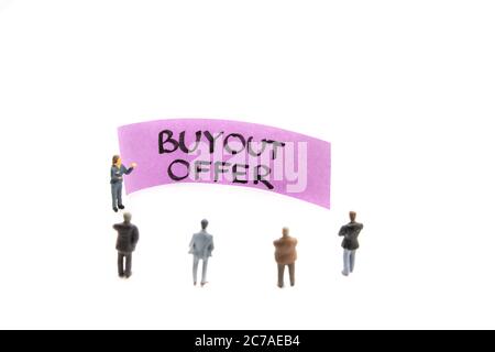 Strategy meeting with miniature figurines posed as business people standing around post-it note with Buyout Offer message on white background, minimal Stock Photo