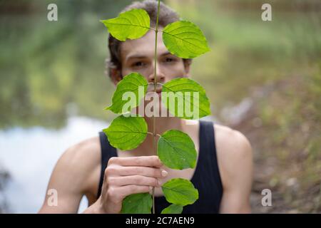 Close-up portrait of man holding leaves in forest Stock Photo