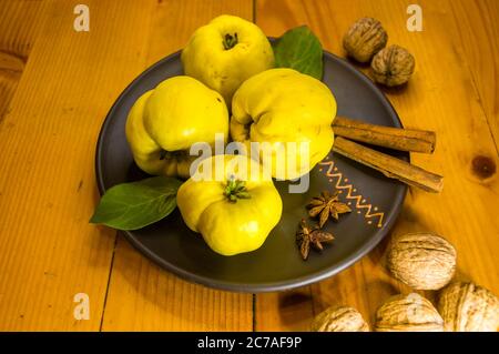 large yellow quince fruits on a ceramic plate, with anise, cinnamon, and walnuts Stock Photo
