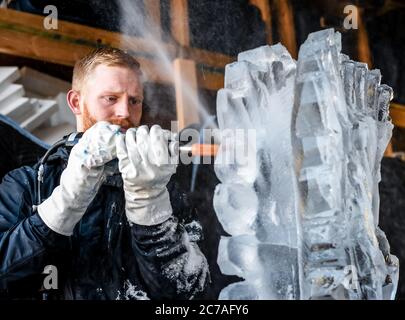 Ice carver sculpting block of ice with electric power dremel Stock Photo