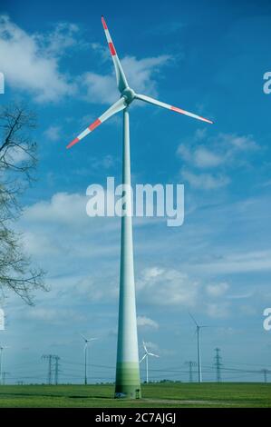 Alternative energy source power generating wind turbines over green field and blue sky Stock Photo