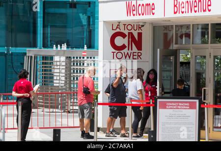 Toronto, Canada. 15th July, 2020. Visitors wearing face masks prepare to enter the CN Tower in Toronto, Canada, on July 15, 2020. After being closed due to the COVID-19 pandemic, the CN Tower reopened to the public starting on Wednesday, with visitors required to wear masks or face coverings inside the tower. Credit: Zou Zheng/Xinhua/Alamy Live News Stock Photo