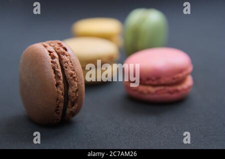 Several macarons of various colors on a table with black color texture and copy space Stock Photo