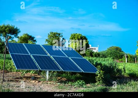 Small Solar Panel Setup Installed In Agriculture Field With Blue Sky, Green environment. Stock Photo