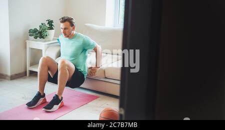 Blond caucasian man wearing sportswear is doing fitness at home Stock Photo