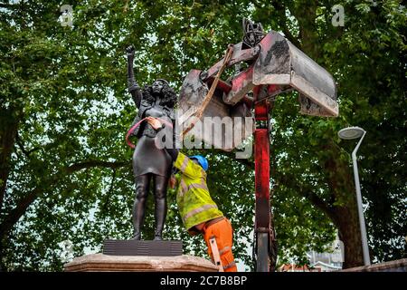 Contractors use ropes to secure A Surge of Power (Jen Reid) 2020, by prominent British sculptor Marc Quinn, which has been installed in Bristol on the site of the fallen statue of the slave trader Edward Colston, as they prepare to remove and load it into into a reCycling and skip hire lorry. Stock Photo