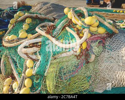 Harbor port with heap of commercial colorful fishing net and rusty steel chain Stock Photo