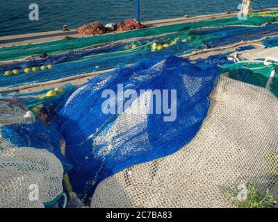 Colored fishing net with floats in industrial port. Fishing net and sea. Stock Photo