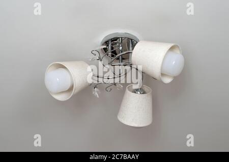Decorative chandelier on the ceiling close-up, silver, three lamps Stock Photo