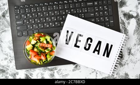 Healthy business lunch snack in office, vegetable salad, VEGAN word on notebook with pen, copy space Stock Photo
