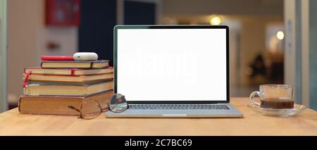 Close up view of study table with stack of books, mock up laptop, smartphone, glasses and coffee cup on wooden table Stock Photo
