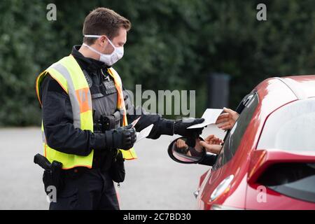 Bautzen, Germany. 16th July, 2020. A policeman checks the ID documents of a driver in the course of a control mission of the Görlitz police headquarters at the 'Löbauer Wasser' motorway parking lot on Autobahn 4. The check is intended to fight cross-border crime on the German-Polish border. Credit: Sebastian Kahnert/dpa-Zentralbild/dpa/Alamy Live News Stock Photo