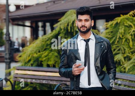 Bearded Indian man on the street using the application in his smartphone. Stock Photo