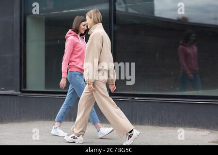 Two girls walking on the city street. Young woman outdoors. Stock Photo