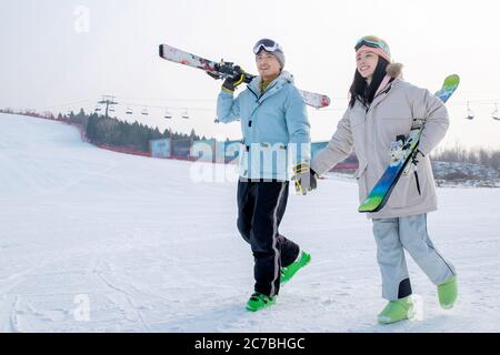 Young couples walking hand in hand with equipment in the ski resort Stock Photo