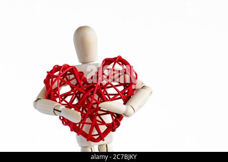 Wooden mannequin holding rattan red heart. White background.  Stock Photo