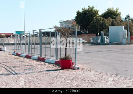 An isolated plant in a red vase on the street near a metallic fence (Pesaro, Italy, Europe) Stock Photo