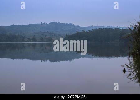 Sunrise view of Lake Nyabikere, with trees growing and the reflections on the water, Rweteera, Fort Portal, Uganda, Africa Stock Photo