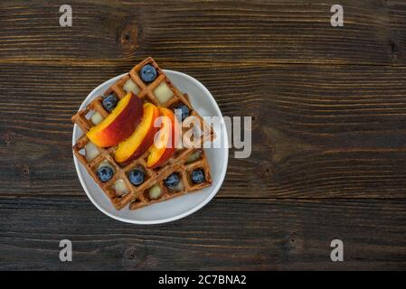 Chocolate Belgian waffles with fruits and berries. Delicious breakfast. Wooden background. Top view, copy space Stock Photo