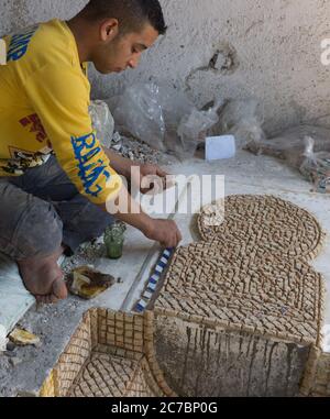 Moroccan Man working on a decorating mosaic in a pottery in Fes, Morocco. Stock Photo