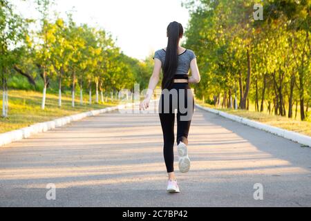 View on back of running woman athlete in the park. Stock Photo