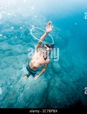 Vertical high angle shot of a male swimming underwater taking out his hand Stock Photo