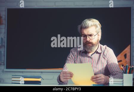 Handsome male teacher checking homework in classroom. Stock Photo
