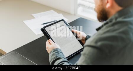 Businessman reading elecronic rental agreement on tablet. Stock Photo