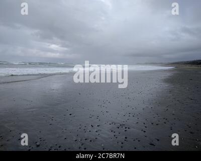 Wide shot of a beach in British Columbia, Canada during overcast, stones scattered along the beach Stock Photo