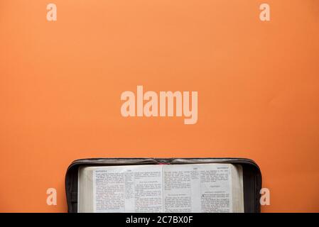 Overhead shot of an open book on an orange surface Stock Photo