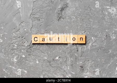 CAUTION word written on wood block. CAUTION text on cement table for your desing, concept. Stock Photo