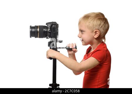 Blond boy shoots video on DSLR camera. Side view. White background, isolate Stock Photo