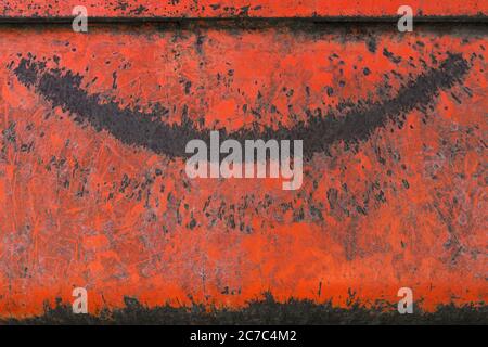 Weathered red metal with a pattern in the shape of a laughing mouth Stock Photo