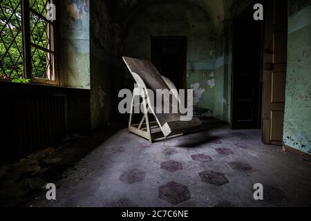 Indoors shot of an abandoned hospital corridor with an old Trendelenburg table in the corridor Stock Photo