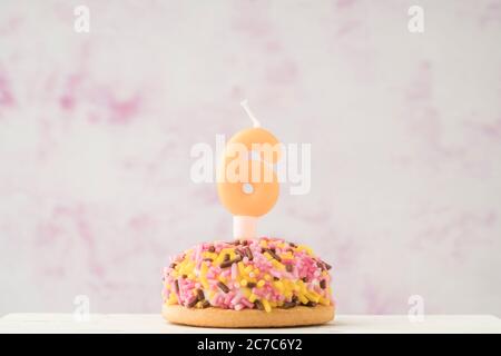 a small coloruful cupcake with number six shaped candle for birthday celebration Stock Photo