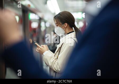 Wearing a mask of the young woman stood on the subway platform Stock Photo