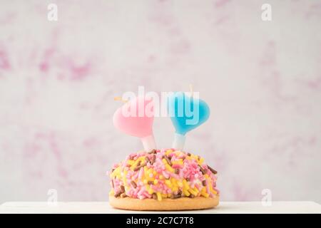 a small coloruful cupcake with heart shaped candles for birthday celebration Stock Photo