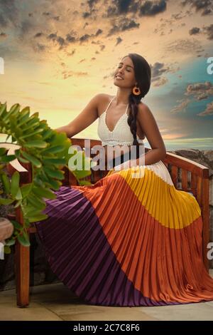 Stunning portrait of beautiful Mexican woman smiling with eyes closed in front of dramatic sunset sky in Puerto Vallarta, Jalisco, Mexico Stock Photo