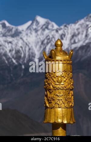 Banner of victory (Dhvaja) on the roof of Buddhist temple in Ranipauwa village, Dhaulagiri Himal in the background. Lower Mustang, Nepal Stock Photo