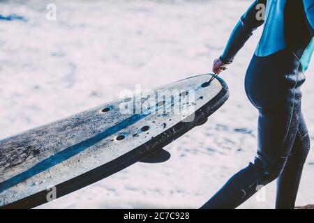 kids enjoying a funny surf day in the shore of a sunny beach in their coastal holidays Stock Photo