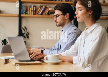 Young pensive business colleagues thoughtfully working on laptop in office Stock Photo
