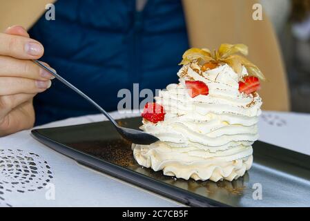 Smiling woman eat Beautiful pavlova cakes with strawberries and spoon in restaurant. Stock Photo