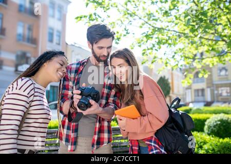 Guy showing pictures and two joyful looking girls Stock Photo