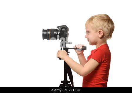 Blond boy shoots video on DSLR camera. Side view. White background, isolate Stock Photo