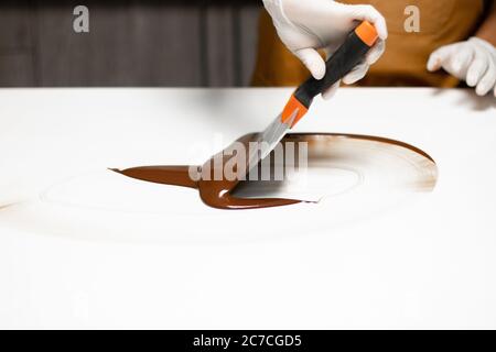 Closeup shot of a chief making delicious tempered chocolate on a white surface Stock Photo