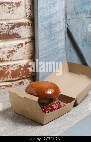 Vertical shot of a hamburger in a paper box with a blurred background Stock Photo