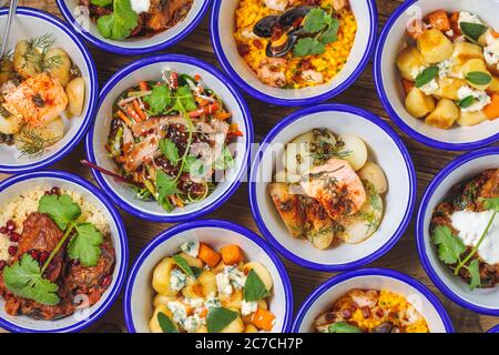 Overhead shot of different types of dishes in bowls near each other on a wooden surface Stock Photo
